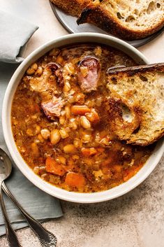 a white bowl filled with soup next to two slices of bread on top of a table