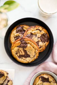 chocolate chip cookies in a black pan next to a glass of milk and napkins