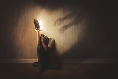 a man sitting on the floor reading a book with his hands in the air while holding an open book