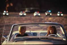 two women sitting in an old car on the road