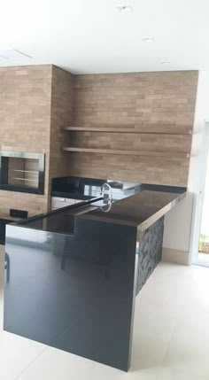 an empty kitchen with black counter tops and stainless steel appliances on the wall behind it