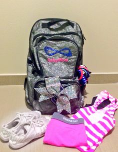 the back pack is sitting on the floor next to some shoes and a bag with a bow