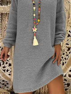 a woman wearing a gray sweater dress with tassels