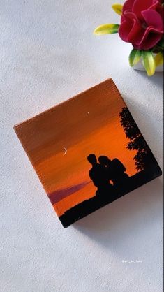 a painting of two people kissing in front of an orange and red sunset with flowers