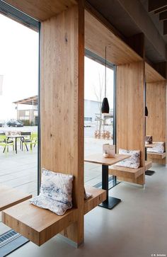 an empty restaurant with wooden benches and glass doors that look out onto the patio area