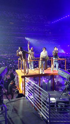 several people standing on top of a platform at a concert