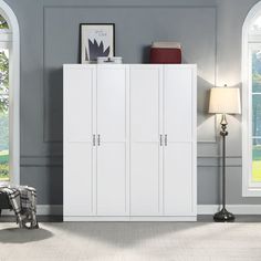 a white cabinet with three doors in a living room next to a chair and lamp