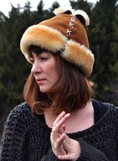 "A playful hat originally designed to accommodate a ponytail emerging from the top of the hat. While this is a fantastic compromise between keeping warm and avoiding hat hair, most fans of this hat don't wear ponytails at all! However, apart from unique styling, we have often heard that fans of this hat like the \"vent\" in the top, citing that it is \"warm, but not claustrophobic.\" This hat is one size, adjustable by tightening or loosening the lacing at the bottom." High Crown Fur Felt Hat For Winter, Winter High Crown Fur Felt Hat, Brown Sheepskin Hat With Faux Fur Lining, Winter Brown Fur Felt Hat Band, Brown Fur Felt Hat Bands For Winter, Brown Curved Brim Costume Hat For Winter, Brown Winter Costume Hat With Curved Brim, Brown High Crown Winter Hat, Lace Ponytail