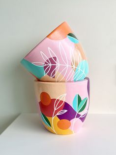 three colorful bowls are stacked on top of each other, with leaves painted on them