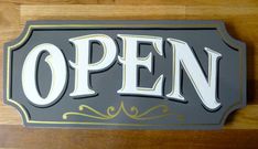 an open sign mounted on the side of a wooden door that says,'open '