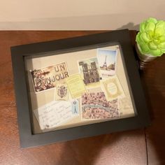 a wooden table topped with a vase filled with flowers and post it notes next to a framed photograph