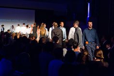 a group of men and women standing in front of a crowd at a fashion show