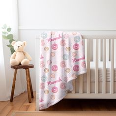 a baby crib with a teddy bear next to it and a blanket on the bed