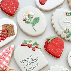 decorated cookies with happy birthday messages and strawberries are displayed on a white tablecloth