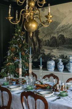 a dining room table is set for christmas dinner with blue and white china on it