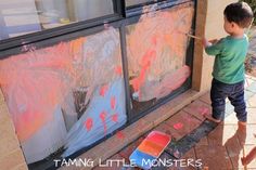 a young boy is painting in front of a window