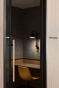 an office with a desk, chair and lamp on the wall next to each other