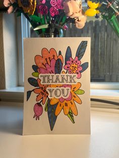 a thank you card with colorful flowers in front of a vase filled with pink, orange and yellow flowers