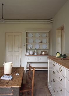 an old fashioned kitchen with wooden table and white cabinets