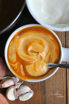 a bowl of soup next to some garlic on a table