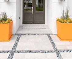 two large orange planters sitting on the side of a white building next to a door