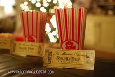 two red and white striped popcorn cups sitting on top of a table next to a christmas tree