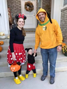 a man and woman in mickey mouse costumes holding hands with a child dressed as minnie mouse