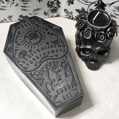 a skull shaped candle holder next to a black and white wallpaper