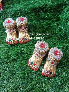 three pairs of gold colored shoes with red stones on the soles and green grass