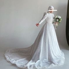 a woman in a white wedding dress holding a bouquet and posing for the camera with her arms outstretched