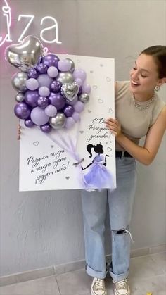 a woman holding up a sign with balloons on it