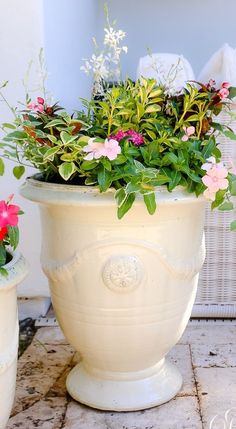 two white planters with flowers in them on a tile floor