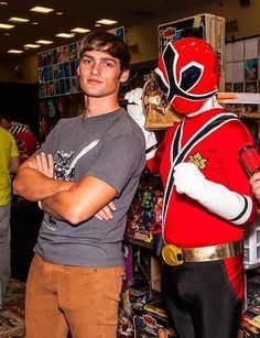 a man standing next to a person in a red power ranger costume at a store