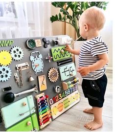 a toddler standing next to a magnetic board with lots of magnets on it