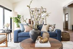 a living room with blue couches and pictures on the wall above them, along with a coffee table