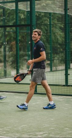 a man walking across a tennis court holding a racquet