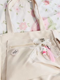 a white purse with a pink and white stuffed animal in it's pocket on a bed