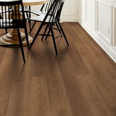 a dining room table and chairs with wood flooring on the walls in front of it