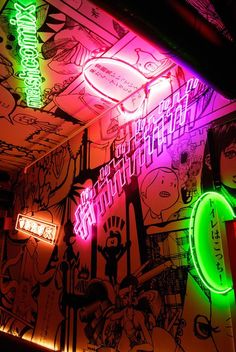 colorful neon signs are lit up on the wall in this dark room with cartoon drawings