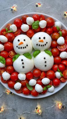 tomatoes and mozzarella in the shape of snowmen on a platter with cherry tomatoes