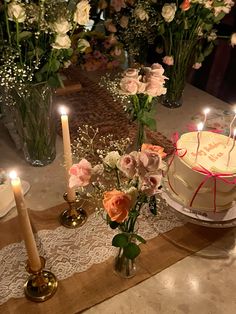 there is a cake on the table with candles and flowers in vases next to it