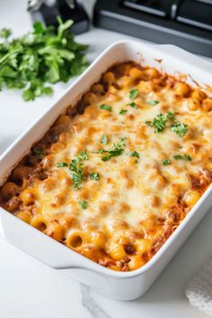 a casserole dish with meat and cheese in it on a table next to some parsley