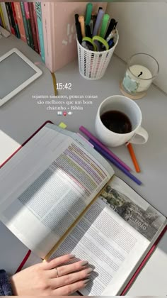 an open book sitting on top of a desk next to a cup of coffee and books