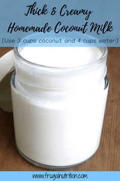 a glass jar filled with homemade coconut milk on top of a wooden table next to a spoon