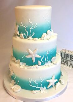 a three tiered cake decorated with starfish and seashells