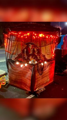 an old fashioned covered wagon with lights on the front and sides, decorated in skeleton decorations