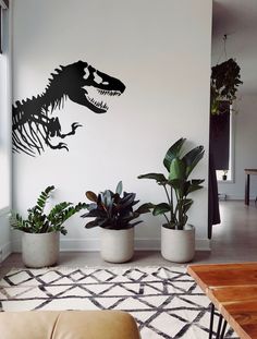 a living room with plants and a dinosaur wall decal