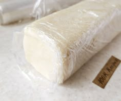 a piece of bread wrapped in plastic on top of a white counter next to a roll of wax paper