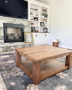 a living room with a fireplace, television and coffee table in front of the fire place