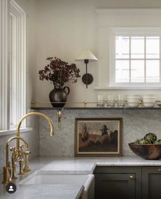 a kitchen with marble counter tops and gold faucets on the wall above it